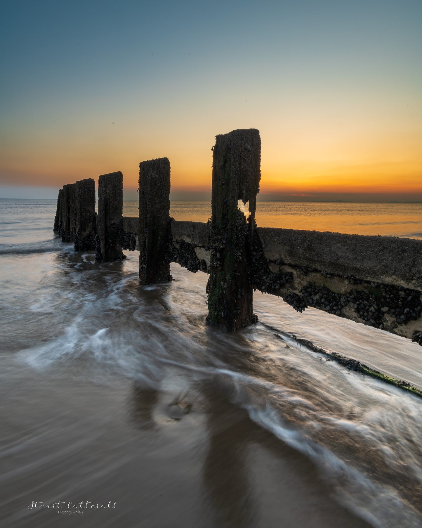 Sea groynes as the sun fades